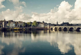 View of a river, historic buildings, and a stone bridge taken from a glamping accommodation by the water.