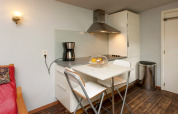 Small kitchenette with dining table, two chairs, coffee maker and storage at The Wijerschans in Belgium.