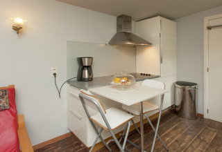 Moderne kitchenette met tafel, stoelen en koffiezet bij The Wijerschans in België.