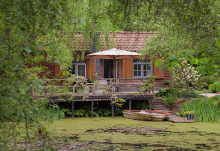 Gezellige hut aan een vijver in België, met terras, bootje en weelderig omgeven door groen.