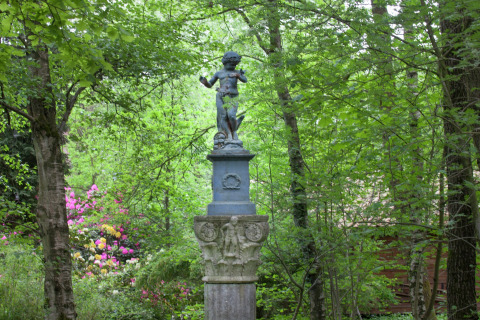 Beeld van een kind op een zuil in het groen bij het boshuisje 'The Wijerschans' in België.