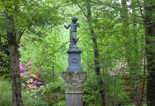 Beeld van een kind op een zuil in het groen bij het boshuisje 'The Wijerschans' in België.
