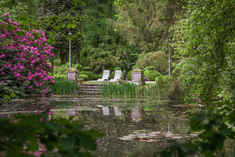 Rustige natuurlijk tuin met vijver en twee stoelen aan The Wijerschans, België, omringd door groen.
