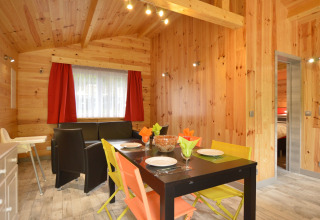 Dining area of Le Chalet Chaleureux A in Belgium with wooden walls, colorful chairs, and a cozy ambiance.