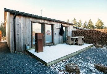 Terrazza esterna presso Chalet Orange con mobili da giardino, neve leggera e alberi sullo sfondo.