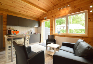 Helles Wohnzimmer und Küche im Le Chalet Chaleureux B in Belgien, mit Holzdecke und modernen Möbeln.