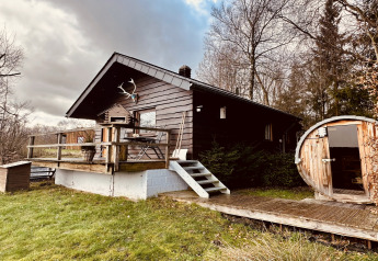 En hyggelig chalet ved navn La Cabane med træterrasse og rund træsauna i naturskønne omgivelser.