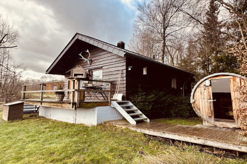 Chalet La Cabane met houten terras en ronde sauna, omgeven door bomen en groene natuur in de buitenlucht.