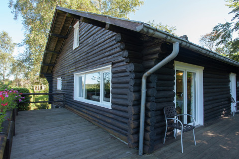 Außenansicht des Chalets Les Muguets mit dunklem Holz, großer Fensterfront und Terrasse.