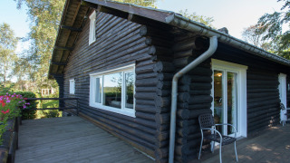 Vista exterior del chalet Les Muguets con troncos oscuros, ventanales y terraza de madera.