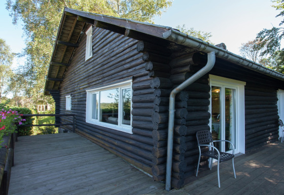 Außenansicht des Chalets Les Muguets mit dunklem Holz, großer Fensterfront und Terrasse.