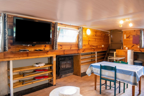 Woonruimte op woonboot 'Le Bateau du Lac Privé' in België met houtafwerking, eettafel en televisie.