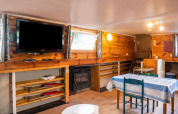 Soggiorno sulla houseboat 'Le Bateau du Lac Privé' in Belgio con pareti in legno, tavolo e televisore.