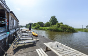 Lettini al sole e tavolo sul ponte di una houseboat presso St Antoine Isera in Belgio, vicino al fiume