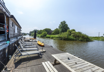 Lettini al sole e tavolo sul ponte di una houseboat presso St Antoine Isera in Belgio, vicino al fiume