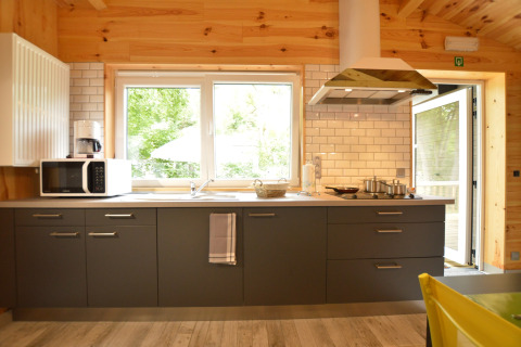 Modern kitchen with grey cabinets, white subway tiles, a microwave, and large windows in Le Chalet Chaleureux A, Belgium.