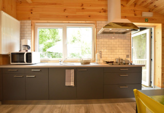 Modern kitchen with grey cabinets, white subway tiles, a microwave, and large windows in Le Chalet Chaleureux A, Belgium.