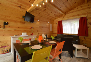 Interior view of cozy Le Chalet Chaleureux A in Belgium, featuring wood walls and colorful chairs.