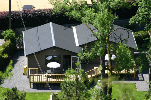 Zwei moderne Glamping-Hütten mit Terrassen und Sonnenschirmen, eingebettet in üppiges grünes Gelände.