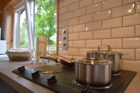 Modern kitchen at Le Chalet Chaleureux A in Belgium, featuring stovetop, pots, and garden view outside.