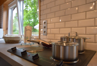 Modern kitchen at Le Chalet Chaleureux A in Belgium, featuring stovetop, pots, and garden view outside.