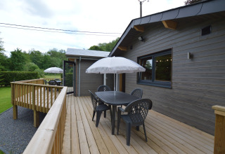 Wooden deck at Le Chalet Chaleureux A in Belgium featuring a patio set with umbrella and scenic views.