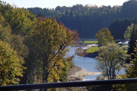 View from Le Chalet Chaleureux A in Belgium, overlooking a river, lush green trees, and tranquil nature.