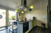 Cucina moderna al Chalet Orange in Belgio, con tavolo da pranzo, lampade verdi e ampia finestra.