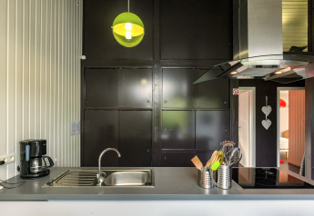 Cucina moderna nello Chalet «Orange» in Belgio con armadi scuri, lampada verde e lavello in acciaio