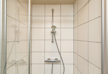 Doccia moderna nel chalet 'Orange' in Belgio, con piastrelle bianche e soffione regolabile.