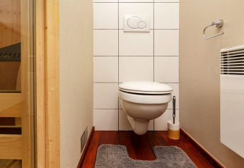 Bagno moderno di chalet con WC sospeso, porta della sauna e termosifone al Chalet Orange in Belgio.