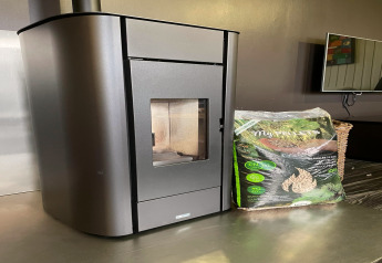 Stufa a pellet moderna e sacco di pellet di legno su un tavolo allo Chalet «Orange» in Belgio.