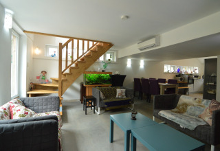Moderne woonkamer in lodge 'Le coeur du brâme' in België met aquarium, trap en eetgedeelte.