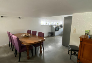 Eetkamer met paarse stoelen en houten tafel, zicht op de keuken bij Le coeur du brâme lodge in België.