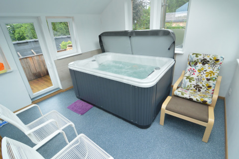 Wellnessruimte bij Le coeur du brâme in België met bubbelbad, comfortabele stoelen en grote ramen.