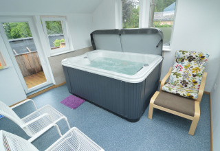 Wellnessruimte bij Le coeur du brâme in België met bubbelbad, comfortabele stoelen en grote ramen.