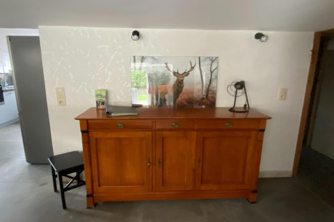 Houten dressoir met een foto van een hert en decoraties, gefotografeerd in een lodge in België.