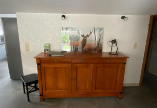 Houten dressoir met een foto van een hert en decoraties, gefotografeerd in een lodge in België.