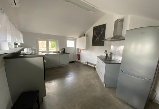 Moderne, ruime keuken met grijze kasten en grote koelkast in ‘Le coeur du brâme’, België.