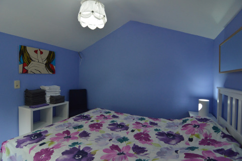 Slaapkamer in lodge ‘Le coeur du brâme’ in België met blauwe muren, bloemenbeddengoed en moderne inrichting.
