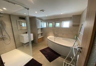 Modern badkamer bij lodge «Le coeur du brâme» in België met douche, bad en kleine ramen.
