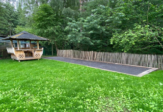 Houten prieel en omheind pad op groen gras, omgeven door bomen bij Le coeur du brâme lodge in België.