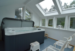 Binnenjacuzzi met grote dakramen in een lichte ruimte van het lodge Le coeur du brâme in België.
