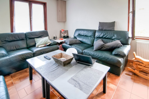 Bright lounge at Au Coeur du Pêcheur in Belgium with leather sofas, a coffee table, and large windows.