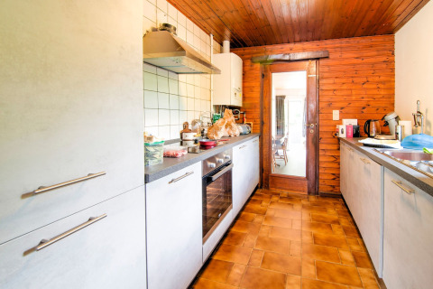 Kitchen at lodge 'Au Coeur du Pêcheur' in Belgium, featuring wood panel walls and modern appliances.