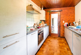 Kitchen at lodge 'Au Coeur du Pêcheur' in Belgium, featuring wood panel walls and modern appliances.