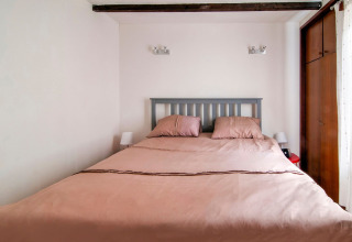 Cozy bedroom featuring a double bed, wooden beams, and natural light at Au Coeur du Pêcheur in Belgium.