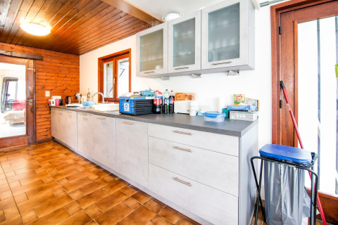 Bright, spacious kitchen at the lodge «Au Coeur du Pêcheur» in Belgium with modern cabinets and wood ceiling.