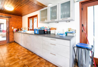 Bright, spacious kitchen at the lodge «Au Coeur du Pêcheur» in Belgium with modern cabinets and wood ceiling.