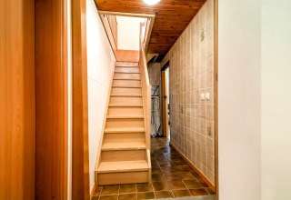 Wooden staircase and hallway in the lodge «Au Coeur du Pêcheur» in Belgium, featuring tiled walls.